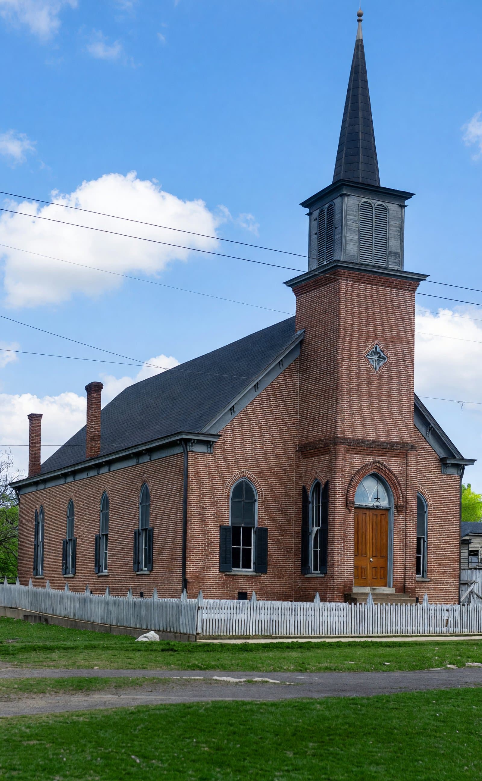 Wartrace Baptist Church, a red brick church with a tall steeple and white picket fence